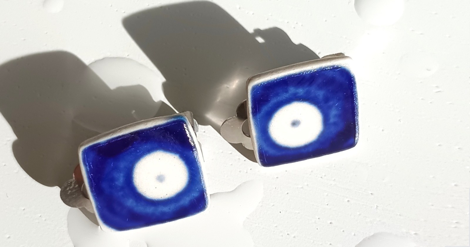 Kwadratowe klipsy, które wykonałam z fragmentów ceramiki bolesławieckiej (dekoracja nr 42). Kawałki stłuczki oszlifowałam i połączyłam z metalowymi zapięciami w kolorze srebrnym