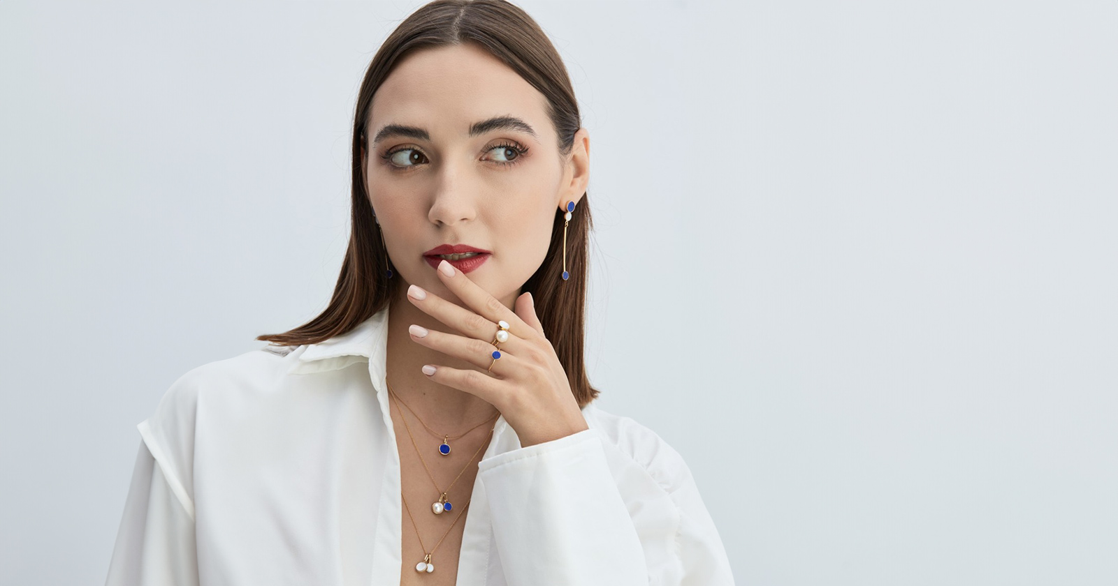 Kobieta w minimalistycznej biżuterii z lapis lazuli. Kolczyki z lapis lazuli. Pierścionek z lapis lazuli i naszyjnik z lapis lazuli