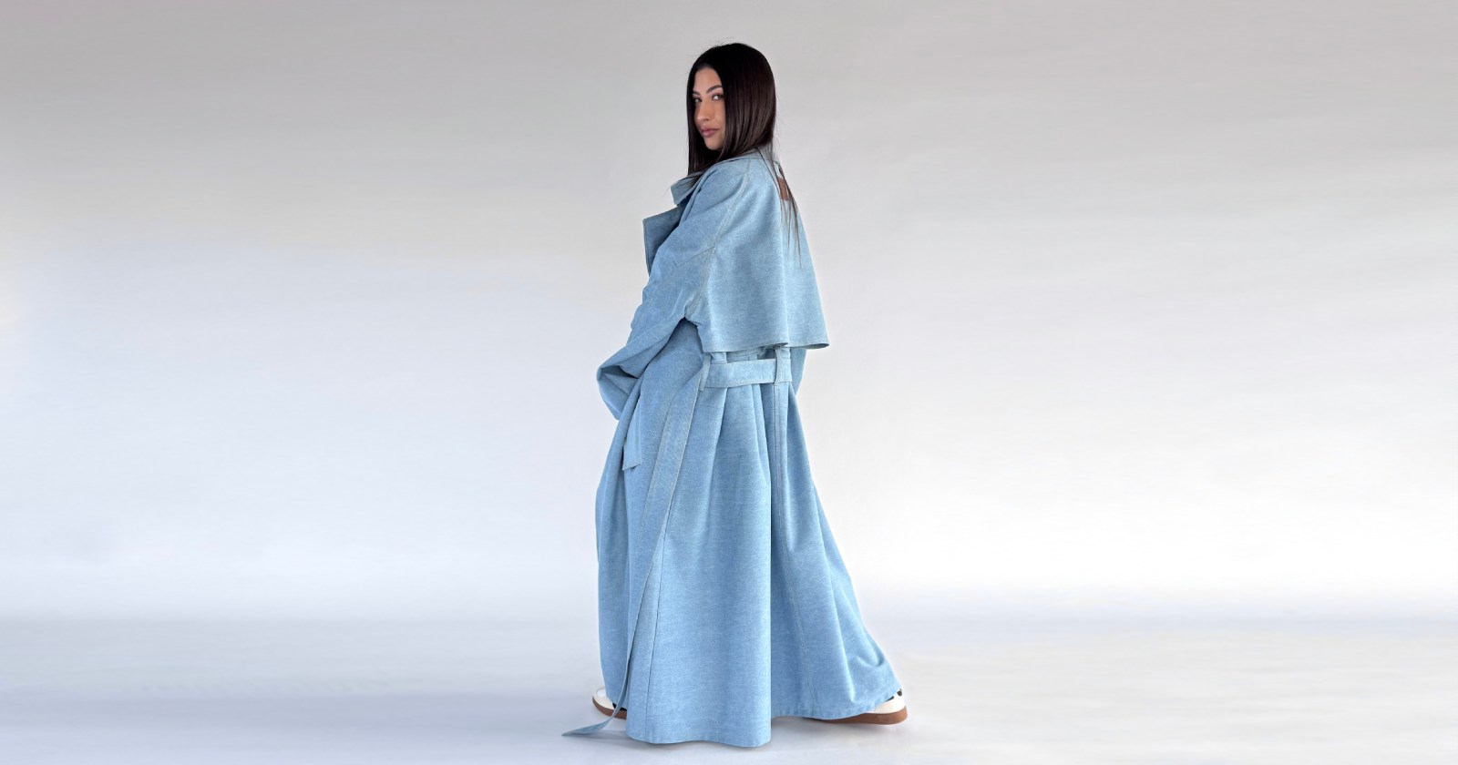płaszcz, trencz maxi, wykonany w całości z jeansu, w kolorze light denim, Mocno oversize'owy krój, obniżona linia ramion, duży kołnierz, szerokie i przerysowane rękawy wykończone gumką oraz metalowym stoperem