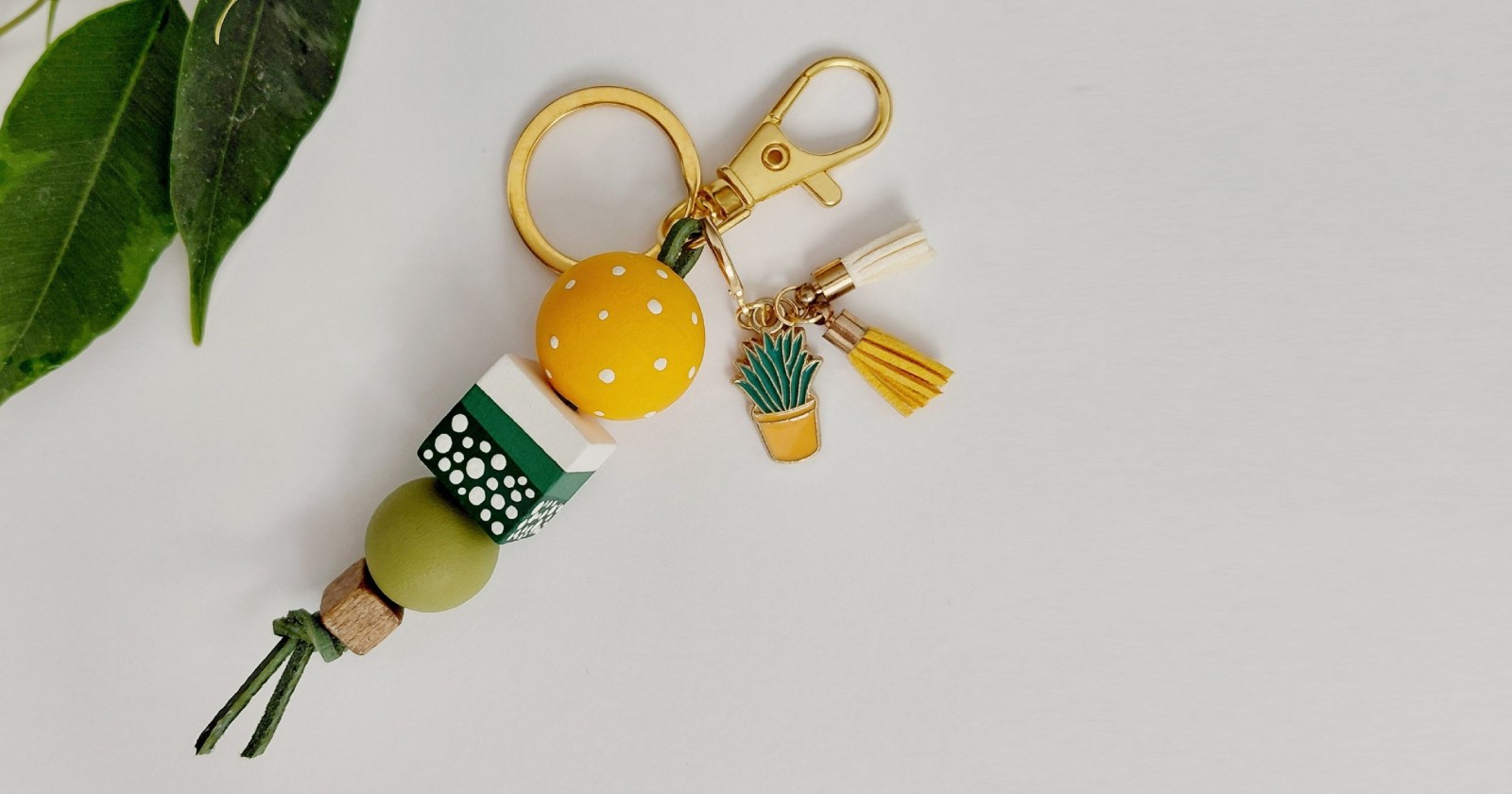 Brelok wykonany z elementów drewnianych malowanych i zabezpieczonych lakierem. Karabińczyk w kolorze złotym.