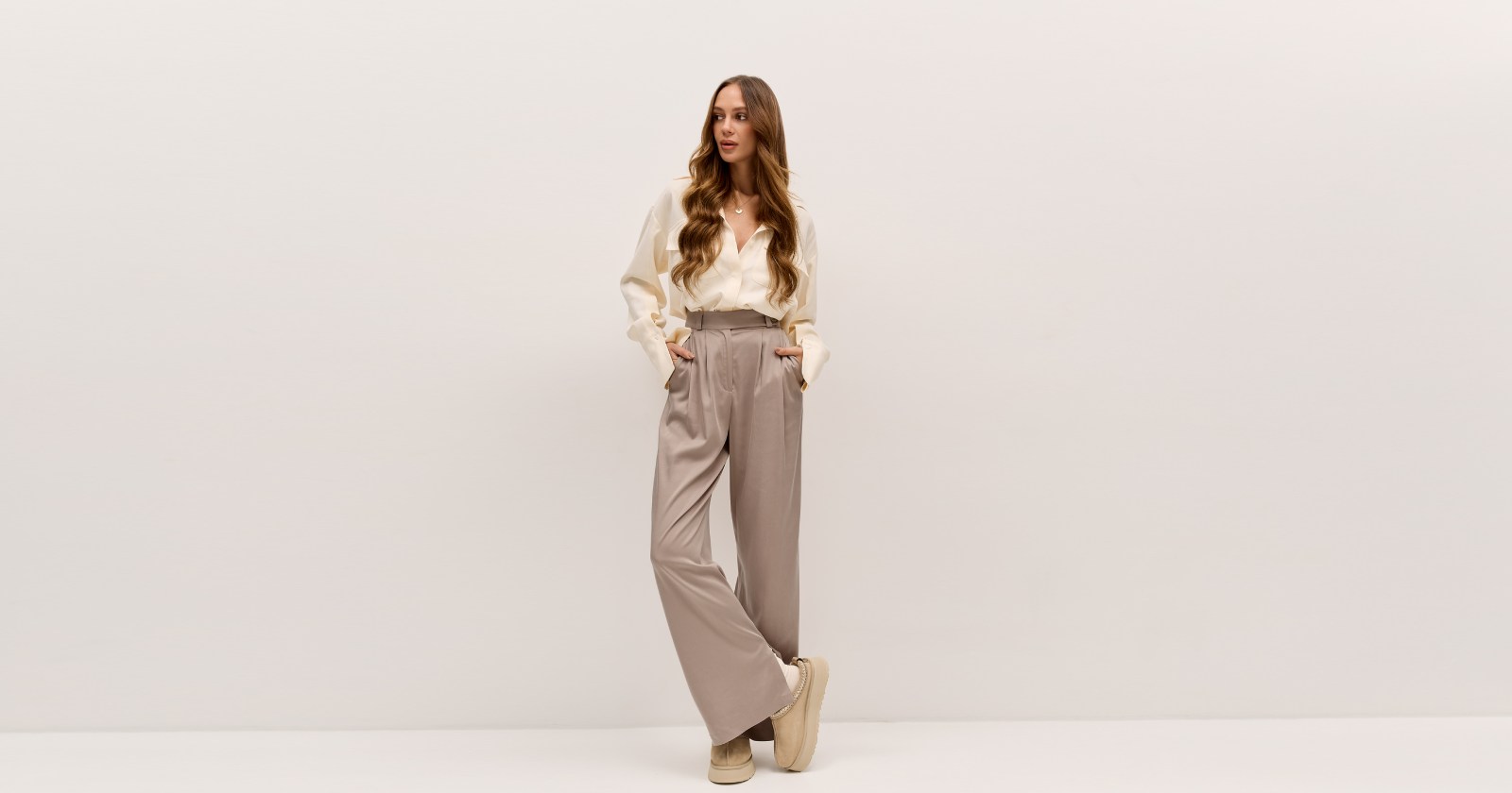 Ponadczasowe spodnie o luźnym kroju z wysokim stanem i licznymi zakładkami. PAYA to spodnie szyte z wysokiej jakości, lekko połyskującej tkaniny. Rozporek od wewnętrznej strony nogawki przełamuje monotonię, odkrywając lekko buty i dodając nogawce lekkości